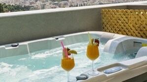 Ein Whirlpool mit zwei Getränken, Blick auf die Stadt und einer Holzterrasse.