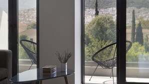 Ein modernes Zimmer mit Balkon, einem Tisch mit Blumenvasen und zwei schwarzen Stühlen.