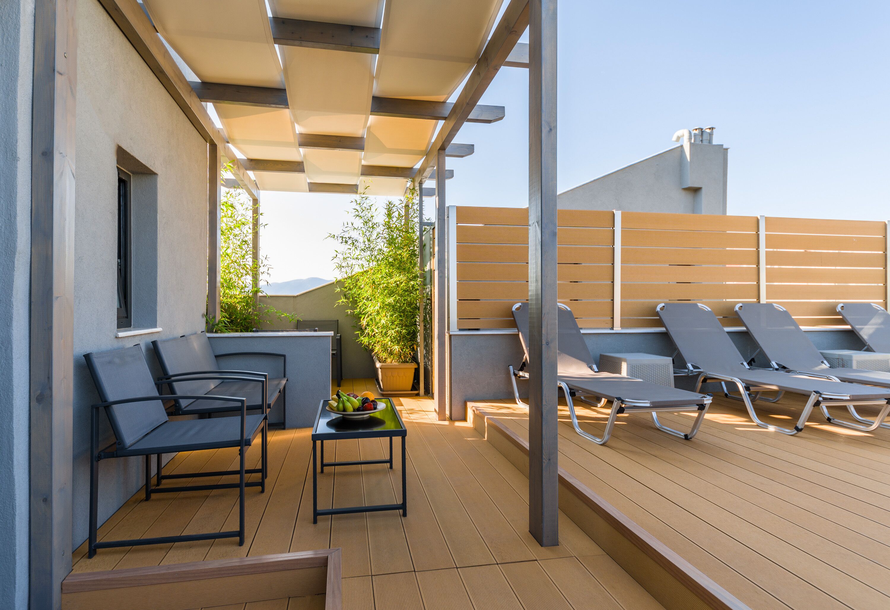 Une terrasse extérieure avec des sièges et une table, un pot de fleurs et une vue sur la verdure.