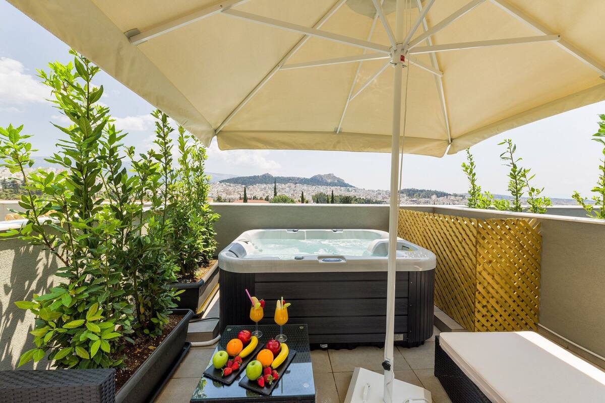 Une terrasse sur le toit avec un jacuzzi, des sièges d’extérieur et une table garnie de fruits et de boissons.