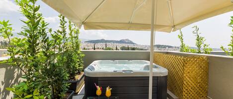 Eine Dachterrasse mit Whirlpool, Sitzgelegenheiten im Freien und einem Tisch mit Früchten und Getränken.