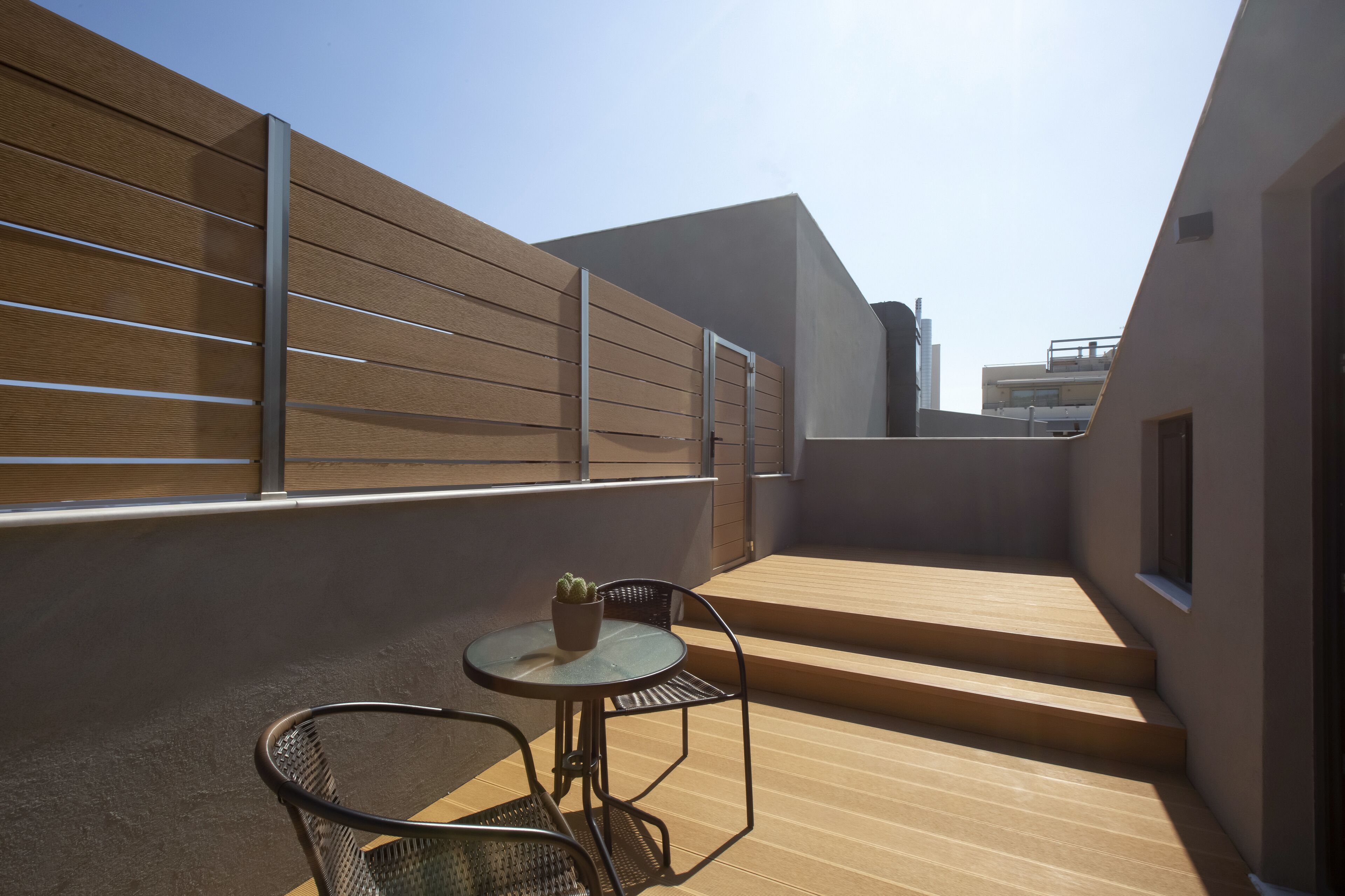 Una terrazza sul tetto con un tavolo e sedie, una pianta in vaso e vista sulla città.