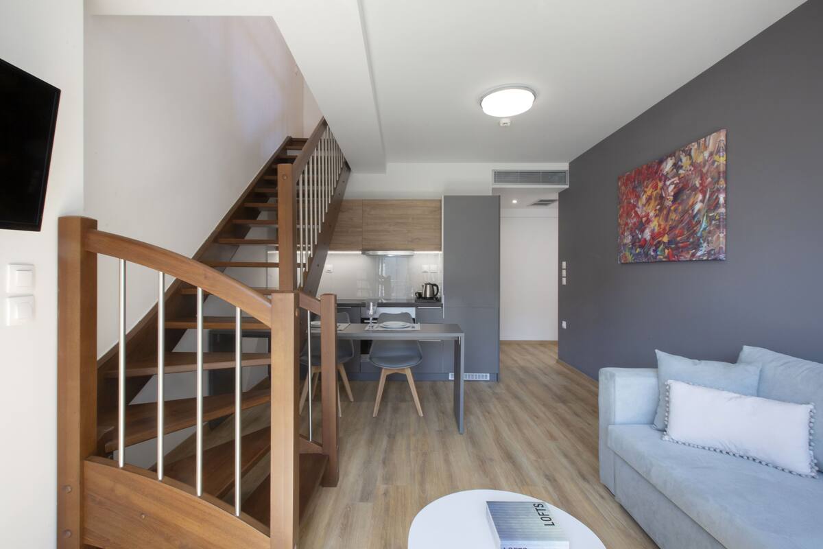 Un salon moderne avec un escalier, un coin repas et une cuisine.
