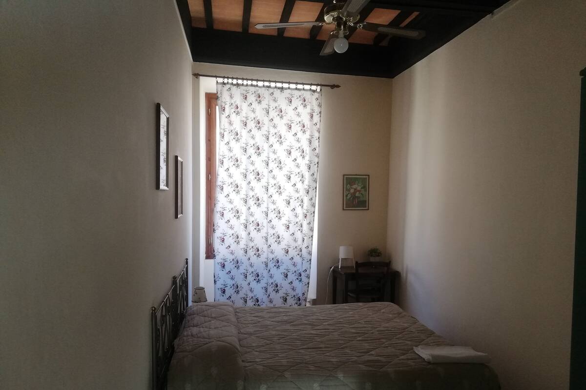 Une chambre à coucher avec un lit, une table de chevet, une lampe et un ventilateur de plafond.