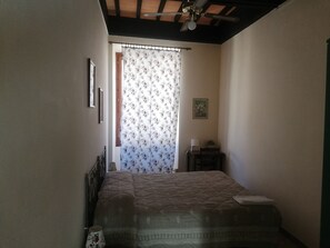 A bedroom with a bed, a nightstand, a lamp, and a ceiling fan. - Albergo Bernini (Siena)