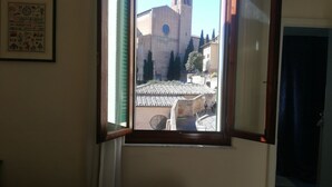 Una habitación con una cama, una ventana con cortinas y un cuadro en la pared.