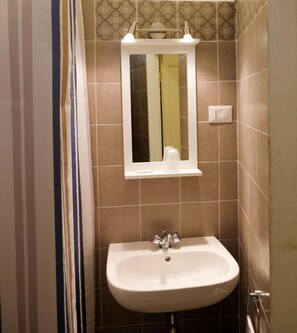 A bathroom with a white sink, a mirror, and a light switch on the wall. - Albergo Bernini (Siena)
