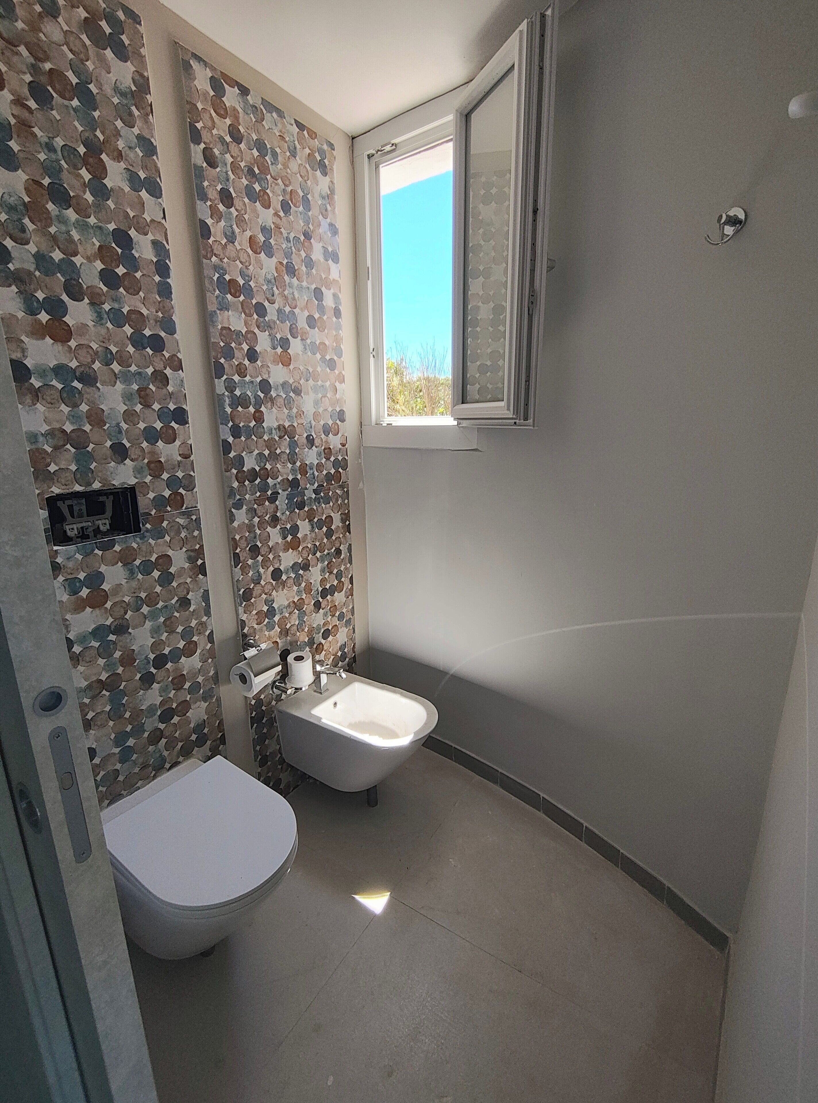 Un baño con inodoro, bidé y ventana.