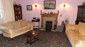 A living room with two sofas, a fireplace, and a patterned carpet. - Pear Tree Farm B&B (Kettering)