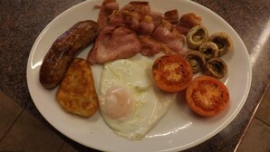 A plate of breakfast food including sausages, bacon, eggs, tomatoes, and mushrooms. - Pear Tree Farm B&B (Kettering)