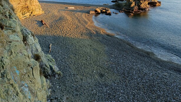 A rocky beach with pebbles and a rocky outcrop.