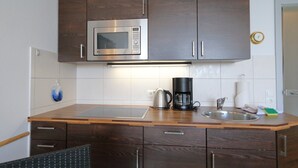 Eine kompakte Küche mit integriertem Mikrowellenherd, einer Kaffeemaschine und einem Spülbecken.