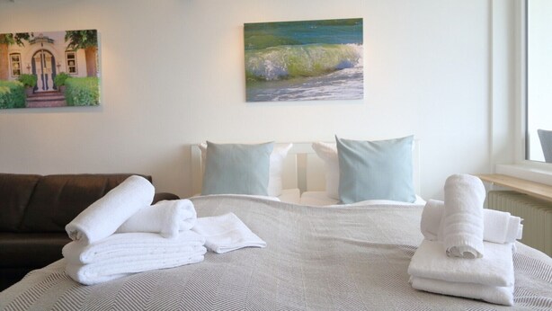 Ein Hotelzimmer mit Bett, Kissen, einer Couch und Handtüchern.