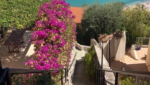 A coastal view with a staircase leading down to a beach, boats in the water, and a clear sky. - Exceptional panoramic view with beach and town on foot (Menton)