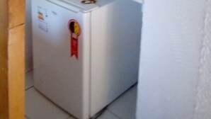 Una habitación compacta con un armario blanco y un refrigerador pequeño.