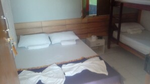 Un dormitorio con cabecera de madera, cama con ropa de cama blanca, una litera y una mesita de noche pequeña.