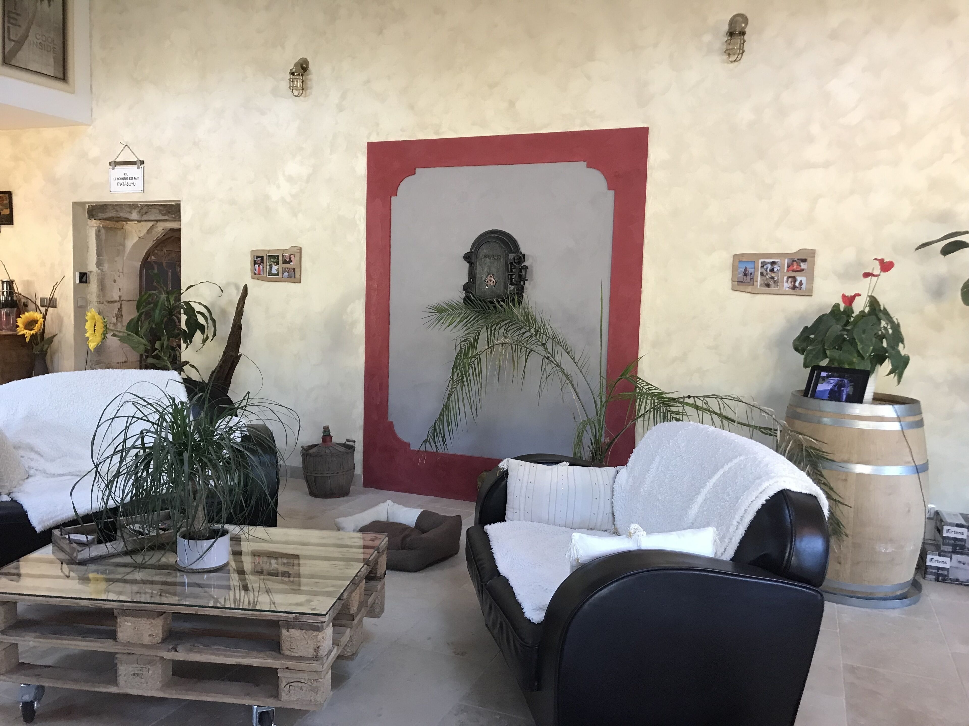 Un salon chaleureux avec une table basse en bois, un canapé noir et une œuvre d’art encadrée de rouge accrochée au mur.