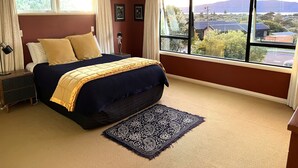 A bedroom with a bed, a nightstand, a lamp, and a view of the outside.