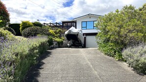 A residential driveway leading to a house with a covered car and a stone wall.