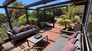 A covered patio area with a sofa, chairs, and a table.