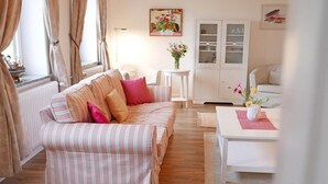 A cozy living room with a striped sofa, a small white table, and a cabinet with glass doors. - "Schleistern" Vacation Rental in Kappeln (Kappeln)
