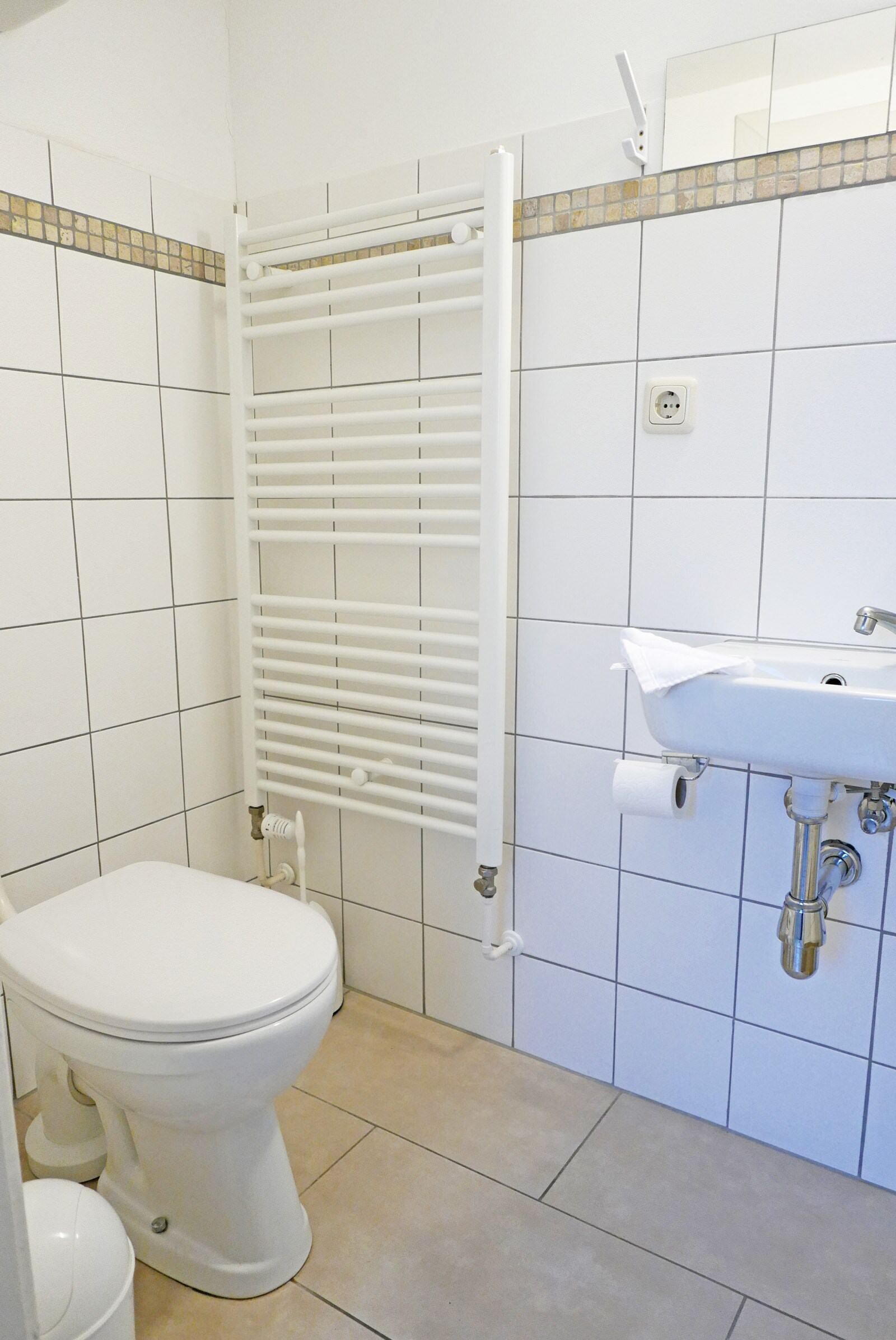 A bathroom with a toilet, a sink, and a towel rack.