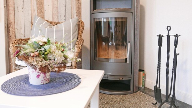 A cozy room with a stone fireplace, wicker furniture, and a floral centerpiece on a table. - "Schleistern" Vacation Rental in Kappeln (Kappeln)