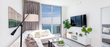 Una sala de estar moderna con sofá, mesa de centro y televisor.