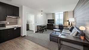Moderni hotellihuone, jossa on keittiö, ruokailutila ja sohva sekä lamppu.