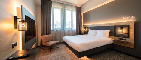 Una habitación de hotel moderna con una cama grande, un escritorio, una silla y un televisor.