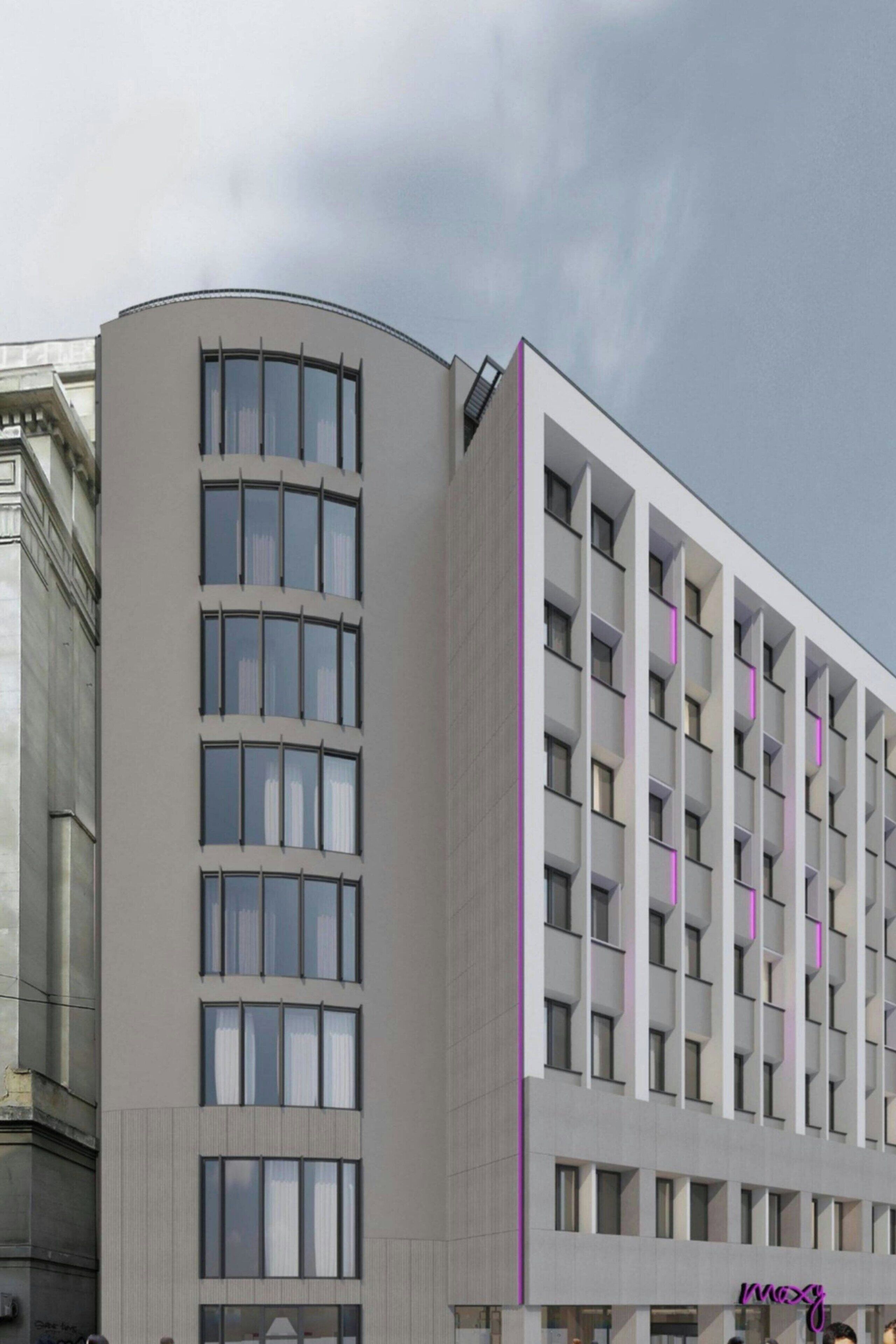 Un hotel moderno con fachada curva, varios balcones y un llamativo letrero que dice 'mozy'.