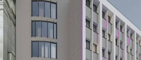 Un hotel moderno con fachada curva, varios balcones y un llamativo letrero que dice 'mozy'.