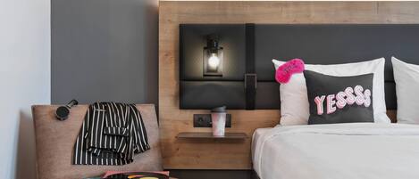 Una habitación de hotel con una cama, una mesita de noche, una silla y un estante en la pared.