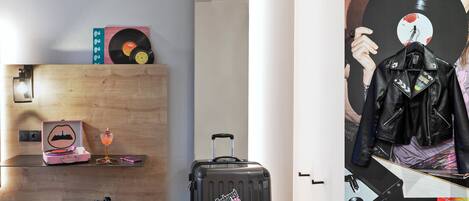 A room with a wooden wall, a suitcase, a record player, and a jacket on a hanger.