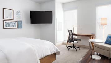 Una camera d'albergo moderna con un letto, una scrivania, una sedia e una televisione.