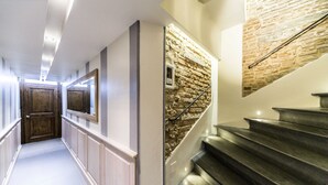 A hallway with a wooden door, a stone wall, and a staircase with a metal handrail. - Love Honeymoon Apartment Piazza Signoria View WiFi AC (Firenze)