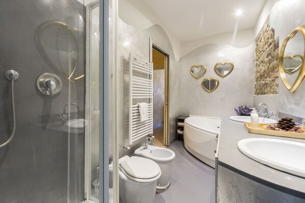 Un baño moderno con ducha de vidrio, un bidé, una bañera y un tocador con lavamanos y espejo.