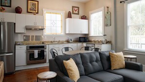 Eine moderne Küche mit weißen Schränken, Edelstahlgeräten und einem Essbereich mit einer schwarzen Ledersofa und einem Holztisch.