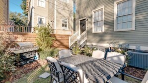 Eine Terrasse mit Tisch, Stühlen, einem Grill und einer Klimaanlage.