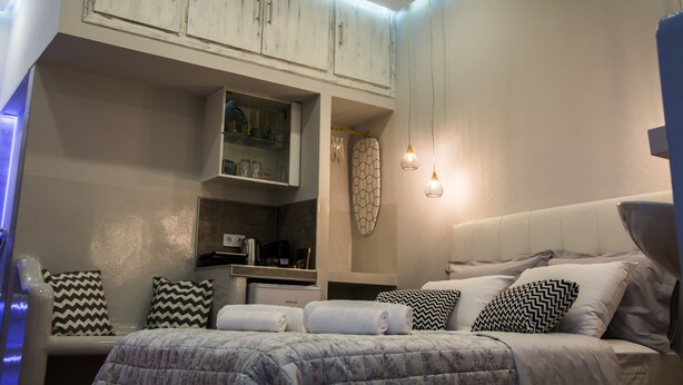 A modern bedroom with a bed, pillows, a wardrobe, and a shelf with items. - Luxury guesthouse nature (Nafplio)