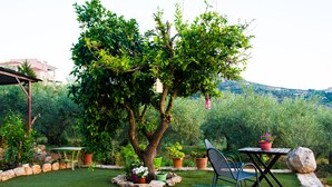 A patio with a table and chairs, surrounded by potted plants and a tree. - Luxury guesthouse nature (Nafplio)