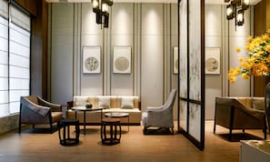 Un intérieur moderne avec un canapé, des fauteuils, une table ronde et des œuvres d’art accrochées aux murs.