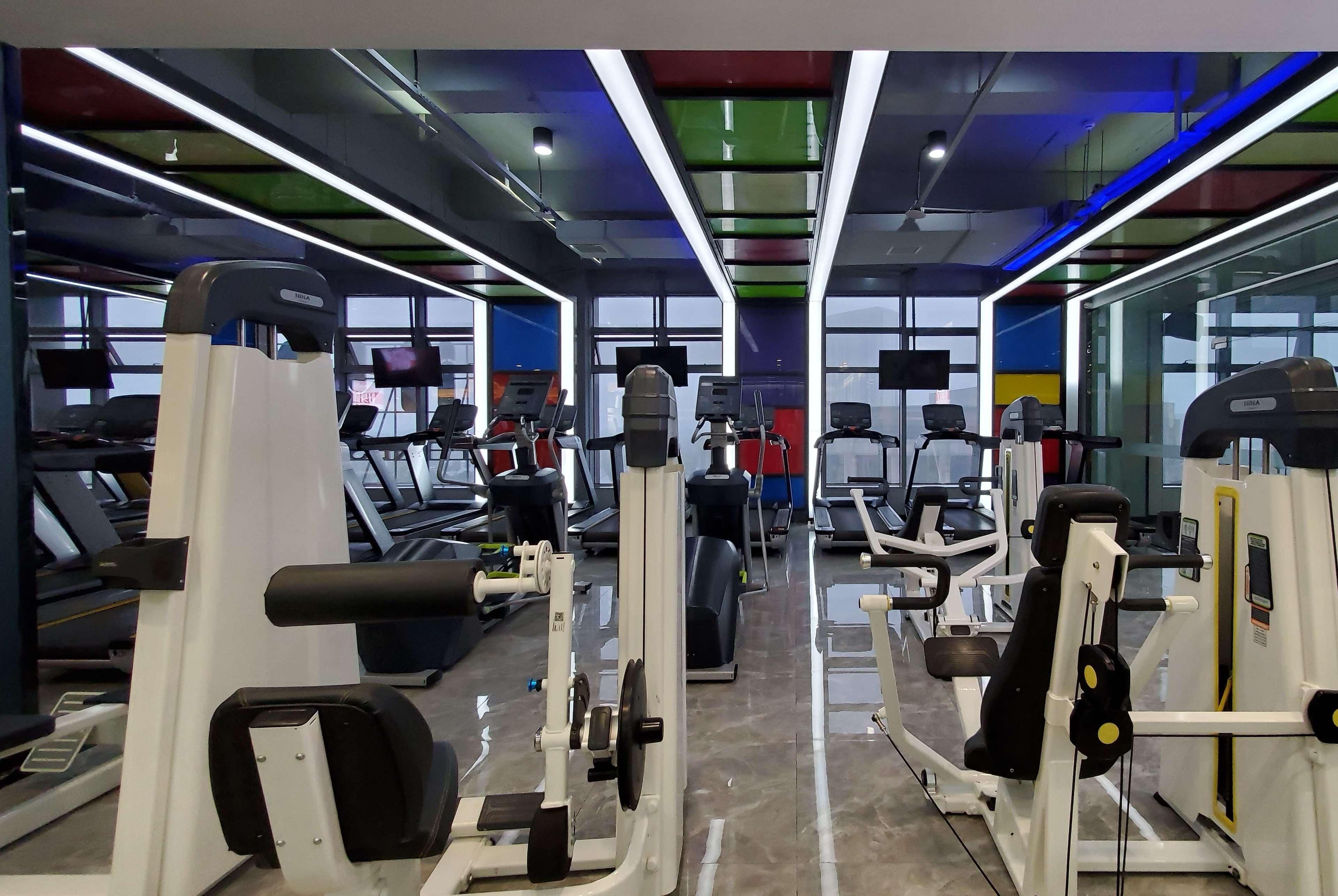 Un gimnasio con cintas de correr, máquinas de pesas y equipamiento de ejercicio.