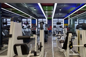 Un gimnasio con cintas de correr, máquinas de pesas y equipamiento de ejercicio.