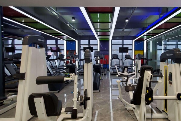 Une salle de sport équipée de tapis de course, d’appareils de musculation et d’autres équipements d’exercice.