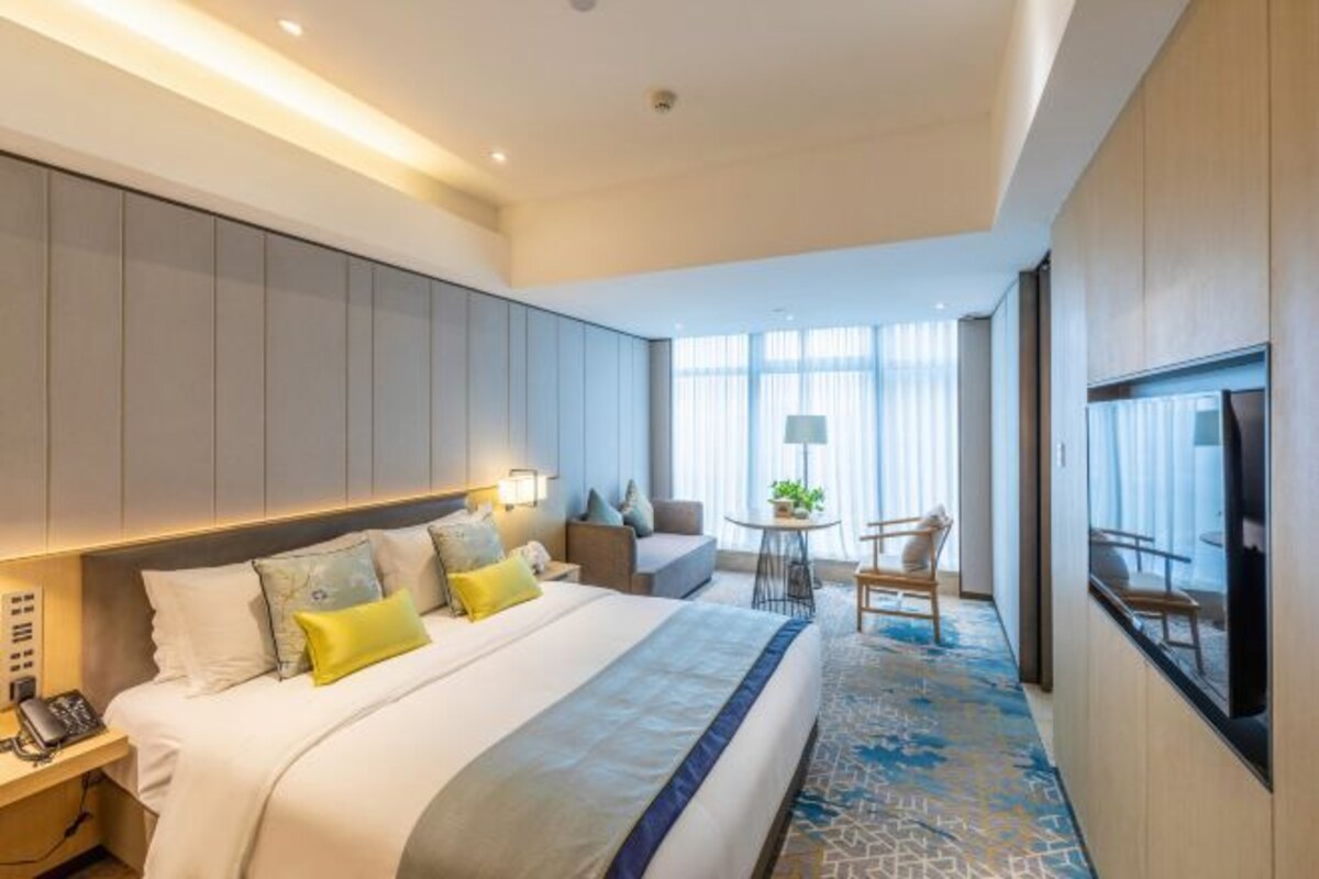 Une chambre d’hôtel moderne équipée d’un grand lit, d’un bureau, d’une chaise et d’un téléviseur.