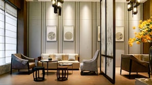 A modern interior with a sofa, chairs, a round table, and artwork on the walls. - Days Hotel Suites By Wyndham Zixin Changsha (Changsha)