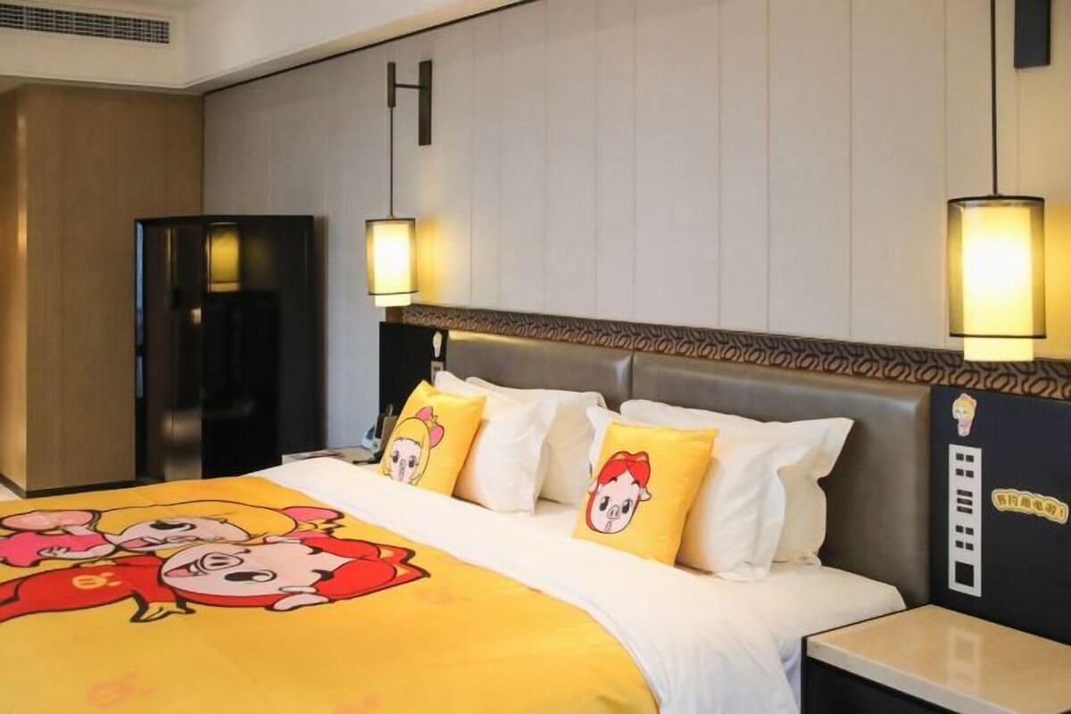 A hotel room with a bed featuring cartoon character pillows, a modern headboard, and bedside lamps.
