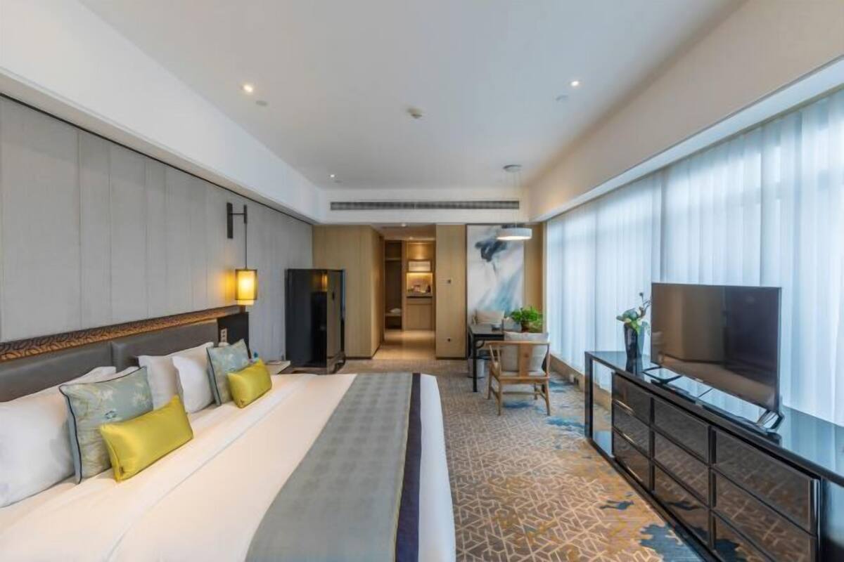 Une chambre d’hôtel avec un grand lit, une télévision, un bureau et une vue sur la ville.