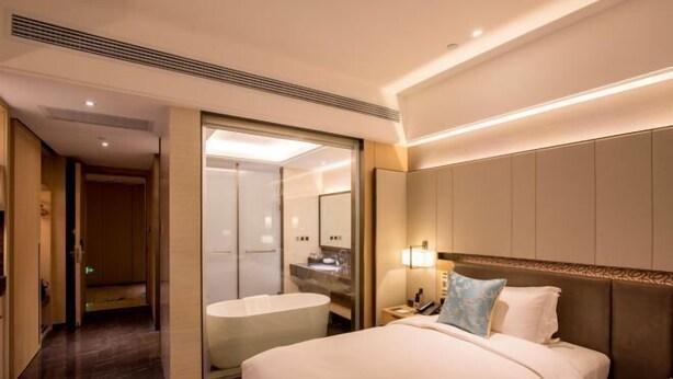 A hotel room with a large bed, a separate bathroom, and a walk-in closet. - Days Hotel Suites By Wyndham Zixin Changsha (Changsha)